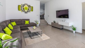 A modern living room with a sectional sofa, a coffee table, a flat-screen TV, and a minimalist design. - Villa in Novigrad With Private Pool (Novigrad)