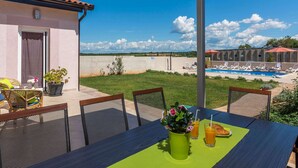 A patio with a table set for breakfast, overlooking a swimming pool and a clear sky. - Villa in Novigrad With Private Pool (Novigrad)