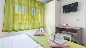 A hotel room with a bed, a desk with a TV, and a window with sheer curtains. - Villa in Novigrad With Private Pool (Novigrad)