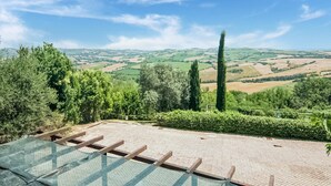 A terrace with a view of rolling hills and a clear sky. - Serene Apartment With Pool (Mombaroccio)