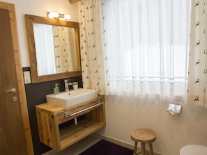 A bathroom with a wooden vanity, a mirror, a sink, and a toilet.