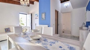 Un coin repas avec une table en bois, des chaises blanches et un mur bleu.