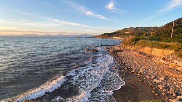Une plage côtière avec un rivage rocheux et une vue dégagée sur la mer.
