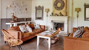 Una sala de estar acogedora con chimenea, una estatua de perro y una pared decorada con platos.