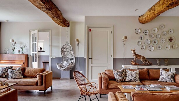 Una sala de estar moderna con un sofá de cuero marrón, una silla colgante y un comedor con mesa y sillas.