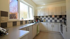 Une cuisine moderne avec des meubles blancs, une grande fenêtre et un pare-feu à carreaux.