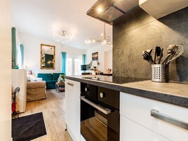 Una cocina moderna con una isla central, armarios blancos y un protector contra salpicaduras de acero inoxidable.
