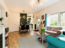 A modern living room with a sofa, a coffee table, and a dining area with chairs and a table.