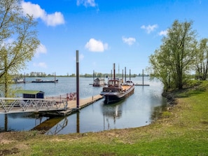 A riverside dock with boats, a small building, and a grassy bank. - Boat Bliss on the Zandmeren Lake (Kerkdriel)