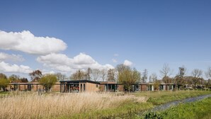 Un ensemble immobilier moderne composé de plusieurs bâtiments, d’une zone verdoyante et d’un petit plan d’eau.
