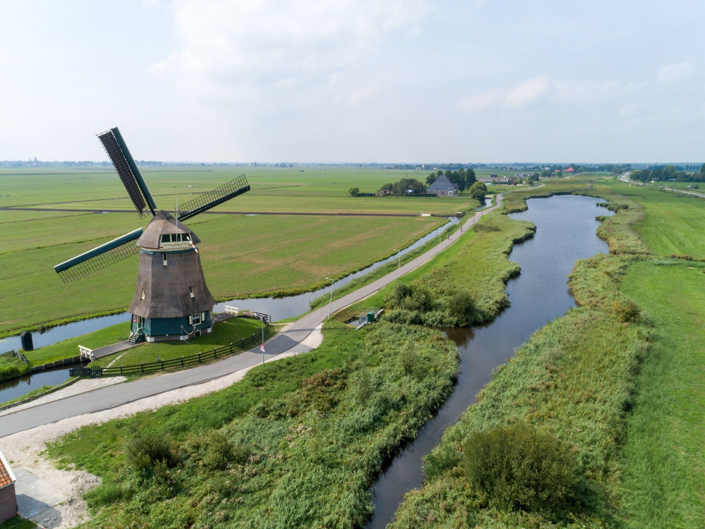 Een traditionele windmolen in een landelijk gebied met een kanaal en velden.