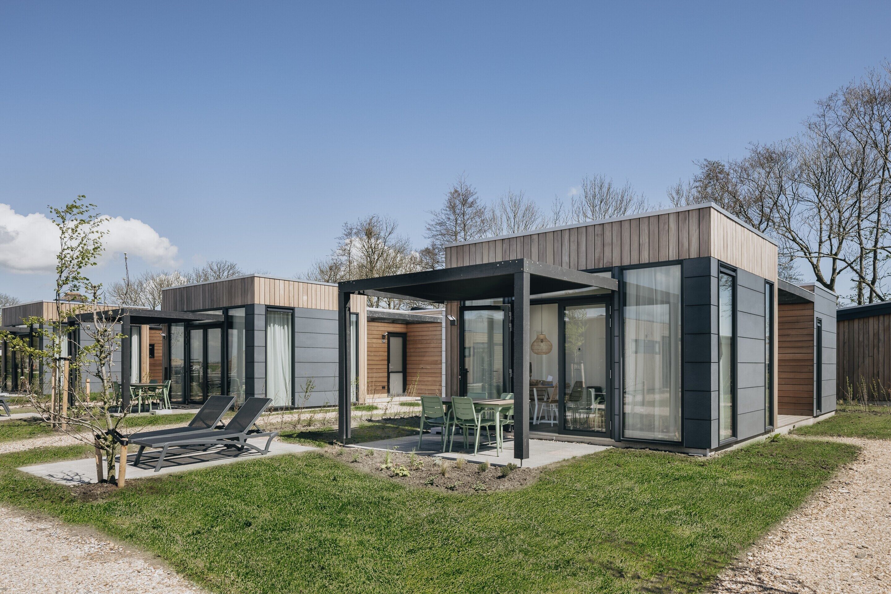 Une maison moderne dotée d’un patio comprenant un espace salon et un barbecue.