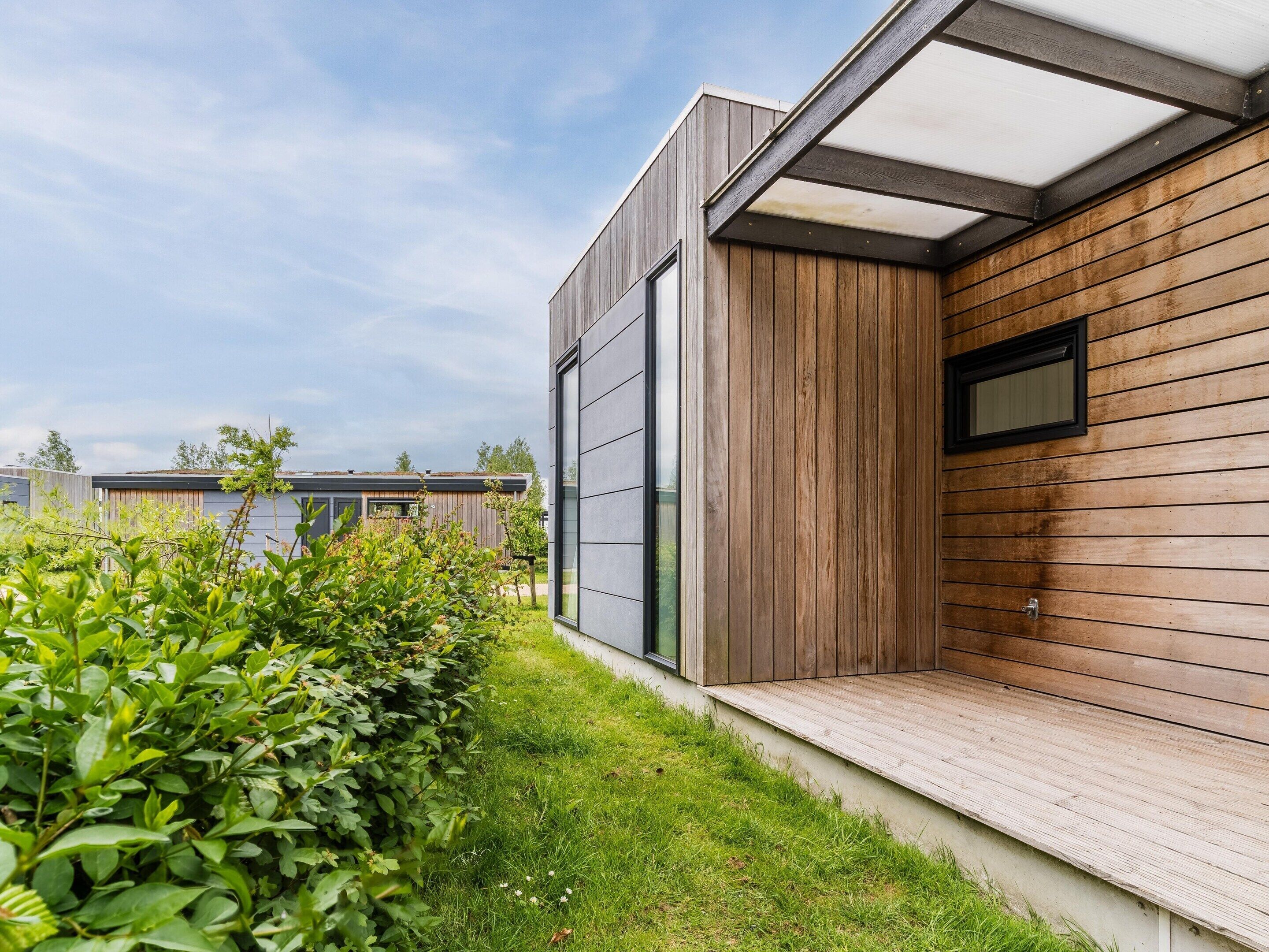 A modern building with a wooden exterior, a glass door, and a small window.
