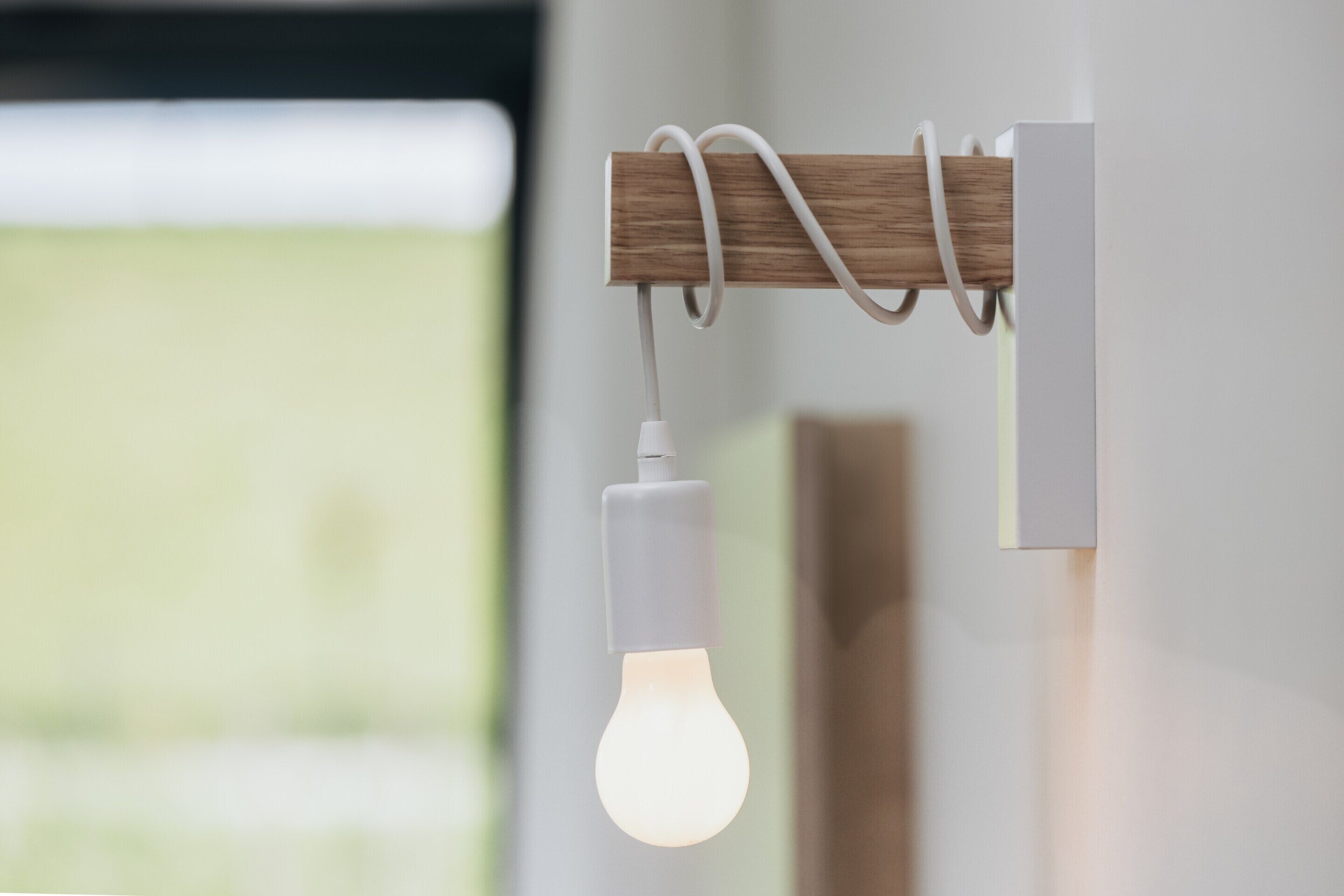 Een moderne lamp met een houten detail en een hangende gloeilamp.