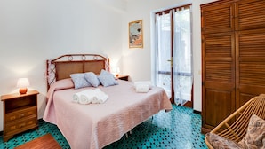A bedroom with a bed, a nightstand, a chair, a wardrobe, and a window with curtains. - Beachfront Villa With Solarium (Siniscola)