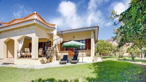 A two-story house with a patio area, outdoor seating, and a covered section. - Beachfront Villa With Solarium (Siniscola)