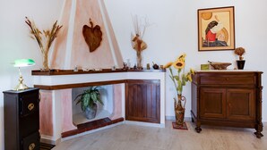 A corner room with a fireplace, a wooden cabinet, a lamp, and a framed painting on the wall. - Beachfront Villa With Solarium (Siniscola)