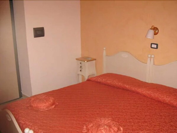 A bedroom with a bed, a nightstand, and a wall-mounted lamp.
