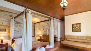 A four-poster bed with a canopy, a wooden bench with towels, a sofa, and a painting on the wall. - Villa in Tavronitis With Pool & Stunning Views (Platanias)