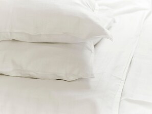 Un lit bien fait, avec du linge de lit et des oreillers blancs.