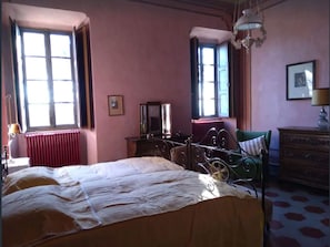 Une pièce comprenant un lit, une commode, une chaise et un radiateur.
