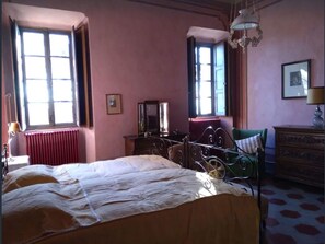 Una habitación con cama, cómoda, silla y radiador.