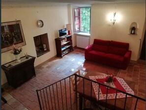 A living room with a red sofa, a TV, a fireplace, and a window with a view of trees.