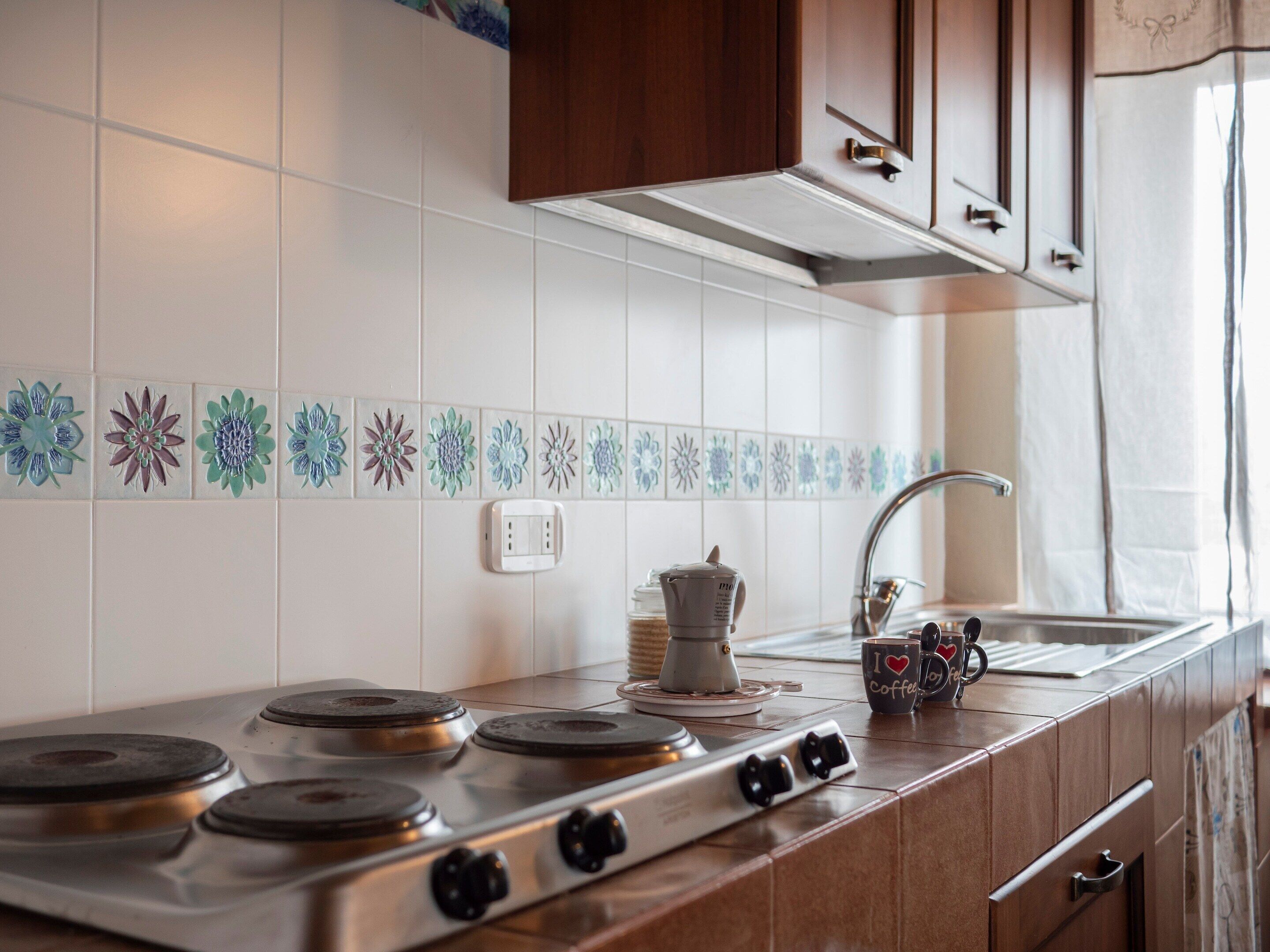 A kitchen with a stove, a sink, and a cabinet.