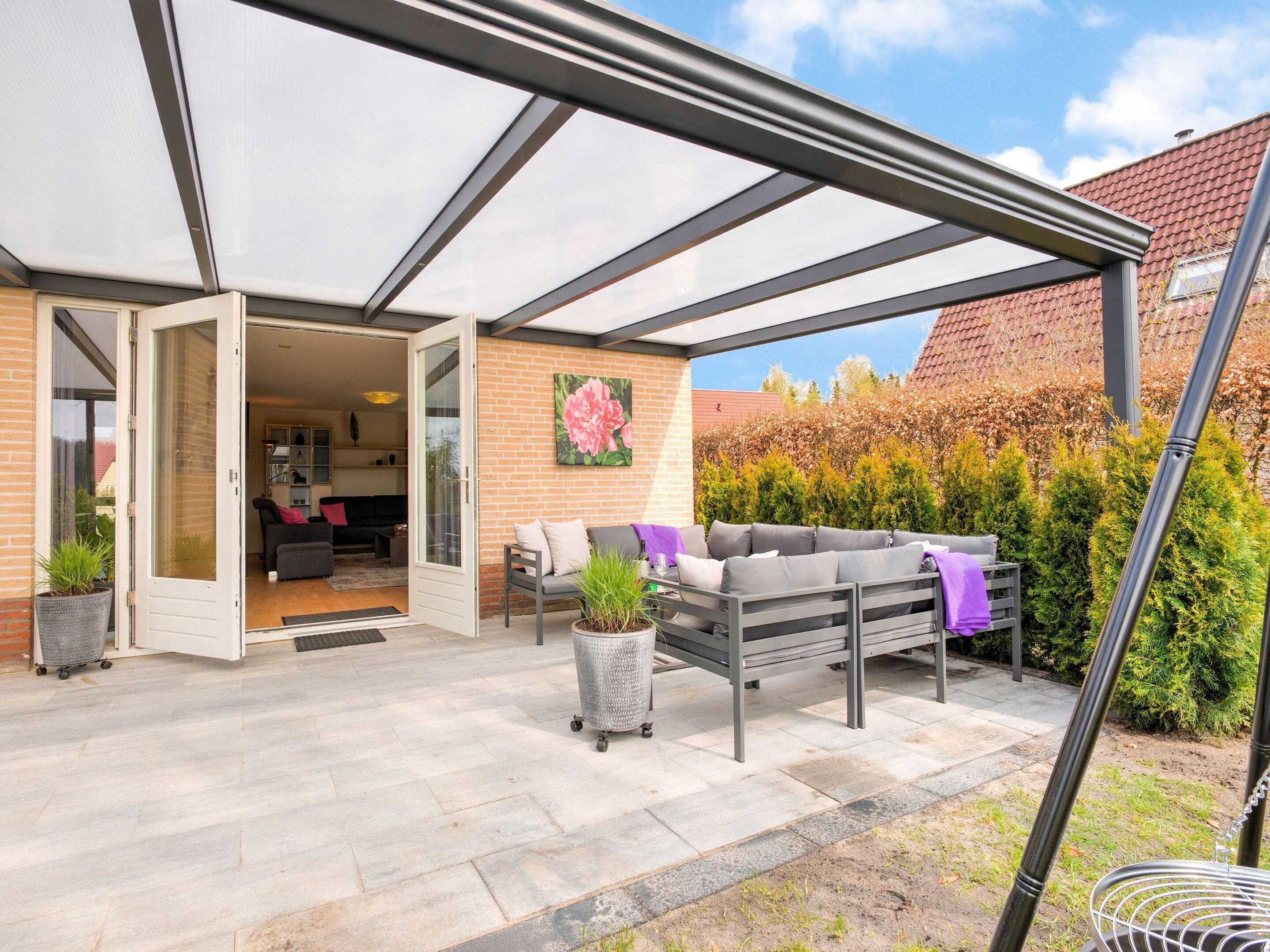 A covered patio area with a seating arrangement and a door leading to an indoor space.