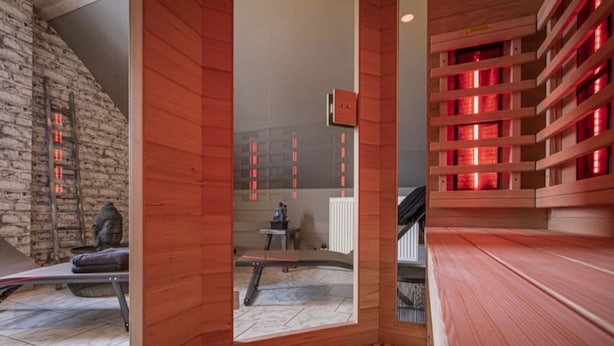 A modern interior with wooden paneling, a stone wall, and a red-lit shelving unit. - Elegant Waimes Mansion Stay (Waimes)