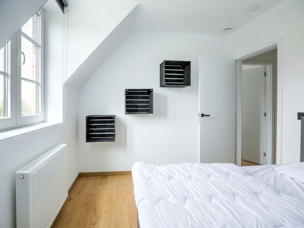A bedroom with a sloped ceiling, a radiator, a bed, and three wall-mounted air vents. - Beautiful House in Flemish Ardennes for Cyclists (Ronse)