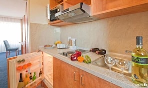 A compact kitchen with a built-in refrigerator, a stove, and a sink.