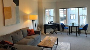 Una sala de estar con un sofá, una mesa de centro y un piano al fondo.