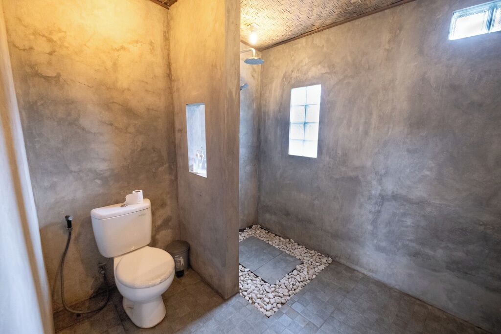 A bathroom with a toilet, shower, and a small window.