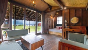 Une pièce spacieuse avec un plancher en bois, un grand lit, un coin salon avec une table et une vue sur l’extérieur.
