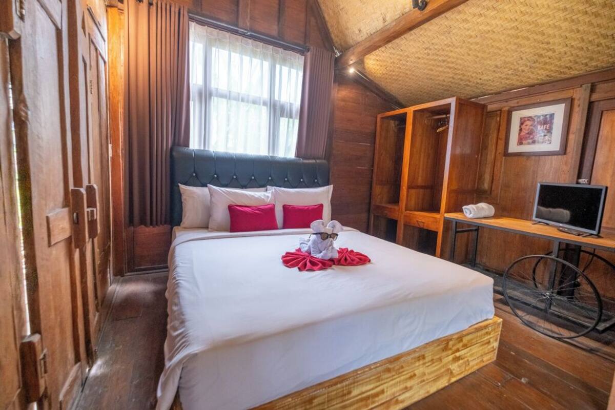 A wooden room with a bed, a desk, and a bicycle.