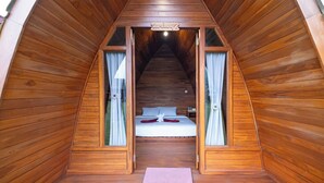 Une cabane en bois avec un lit en mezzanine, une petite table et un banc.