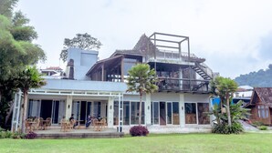 Un bâtiment à deux étages doté d’un balcon et d’un espace extérieur aménagé avec des sièges.