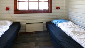 Une chambre avec deux lits, une fenêtre et un radiateur.