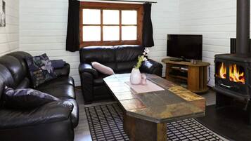 A living room with a fireplace, leather sofas, a coffee table, and a television.