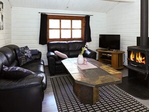 A living room with a fireplace, leather sofas, a coffee table, and a television. - 6 Person Holiday Home in Hadsund (Hadsund)