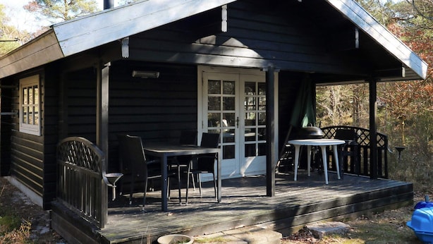 Une cabane en bois avec une véranda, une table et des chaises.