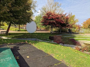 A park with a circular viewing platform, a paved walkway, and a variety of trees including one with red leaves. - 4 Star Holiday Home in Nordborg (Nordborg)