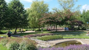Ein Park mit Teich, Spazierwegen und Bänken.