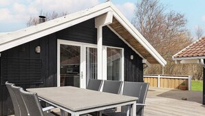 Une terrasse avec une table et des chaises, une porte-fenêtre coulissante et un revêtement de sol en bois.