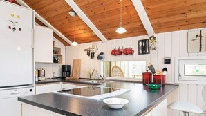 Une cuisine moderne dotée d’un îlot central, de meubles blancs et de poutres en bois au plafond.