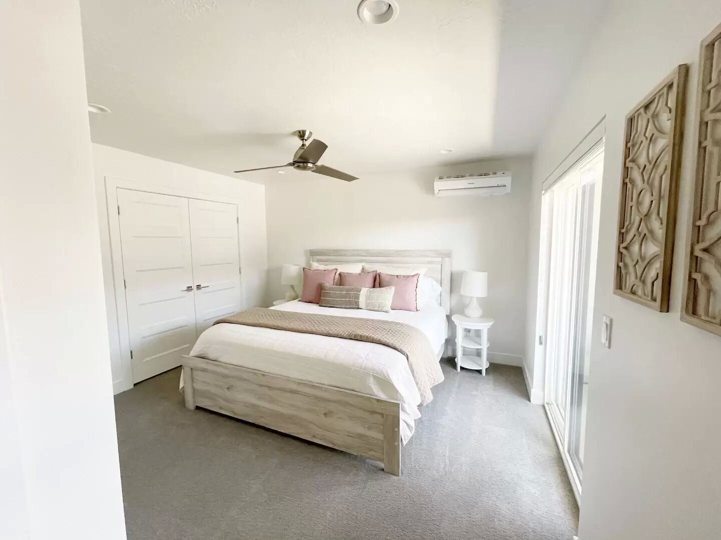 A bedroom with a bed, a ceiling fan, a nightstand, and a wall-mounted air conditioner.