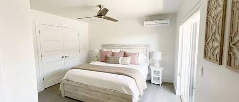 A bedroom with a bed, a ceiling fan, a nightstand, and a wall-mounted air conditioner.