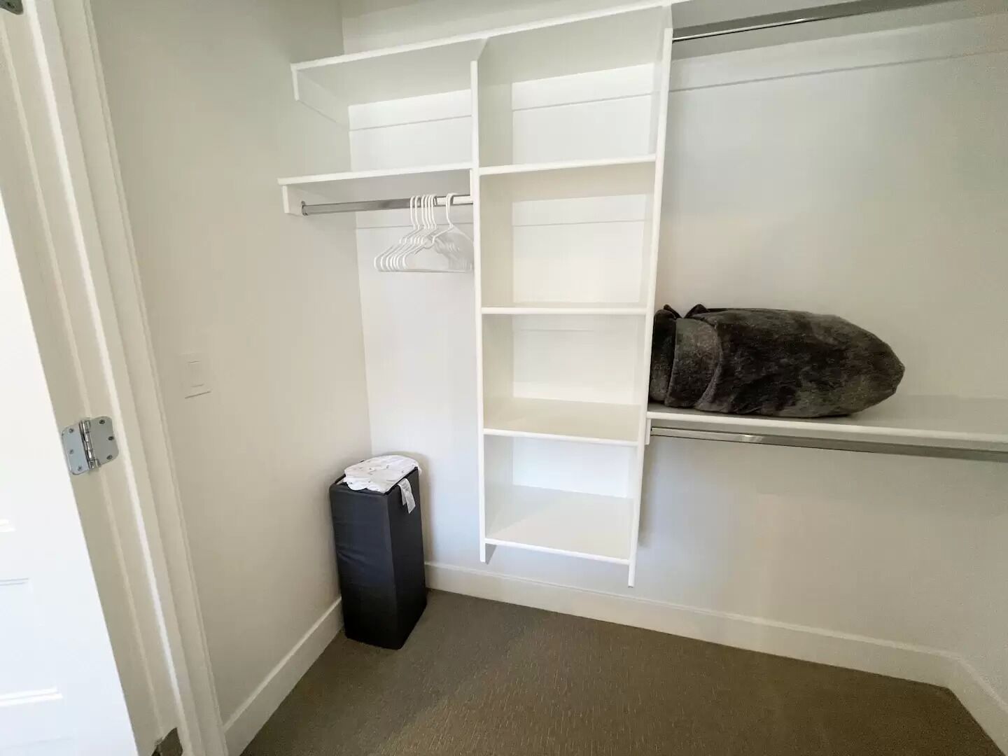 A walk-in closet with white shelving units and a hanging rod.