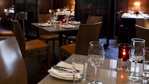 A restaurant interior with tables set for dining, chairs, and candles.